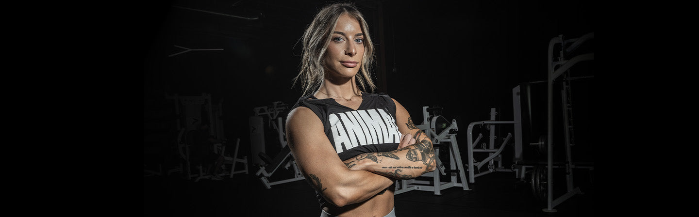 Maddy Forberg with tattoos wearing a black tank top with ANIMAL text